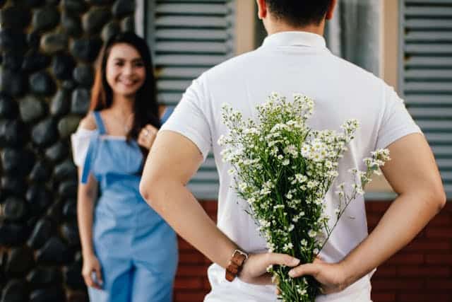 man presenting flowers to woman